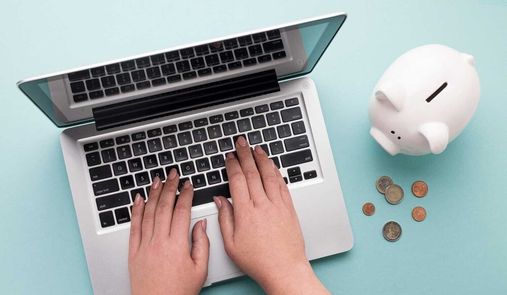 Laptop with a piggy bank and coins representing managed IT support costs and budgeting for a Singapore business